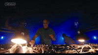 a man is playing music in a dark room with a blue light behind him