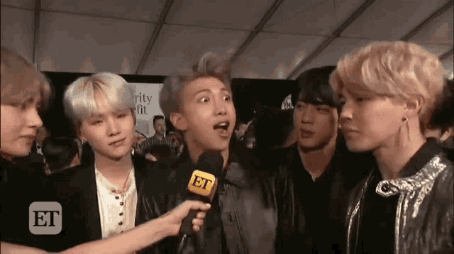 a group of young men are being interviewed by a woman holding a microphone that says et