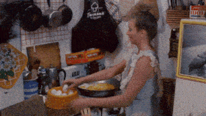 a woman is preparing food in a kitchen with a box of lucky charms on the wall