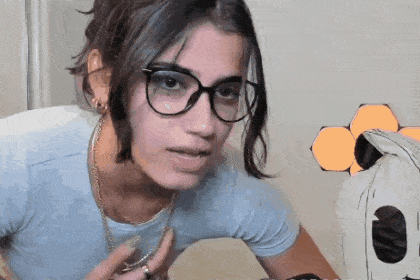 a woman wearing glasses and a blue shirt is making a face