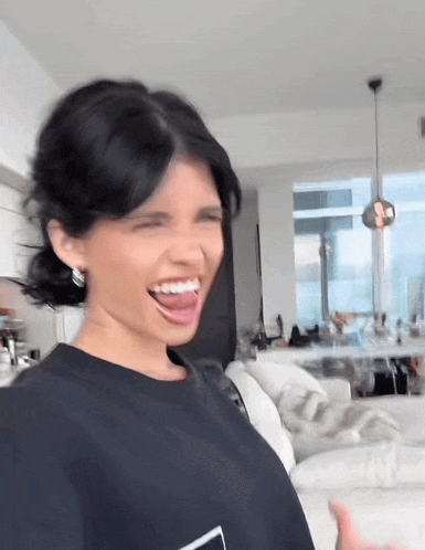 a woman is making a funny face with her tongue out in a living room