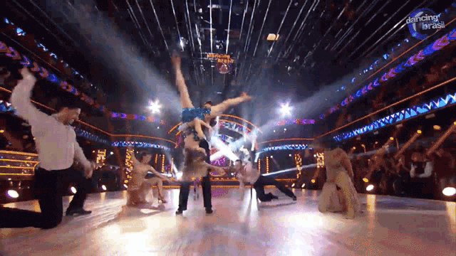 a group of people are dancing on a stage with a sign that says dancing brasil
