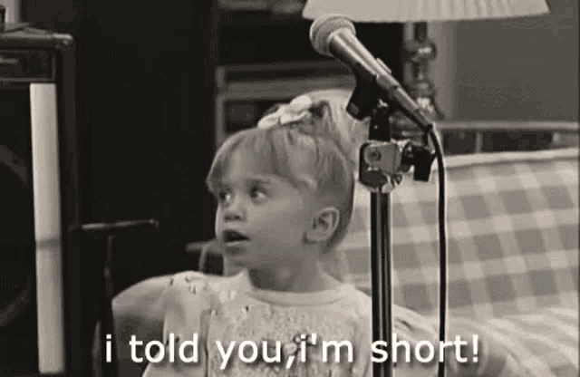 a little girl is singing into a microphone and saying `` i told you , i 'm short '' .