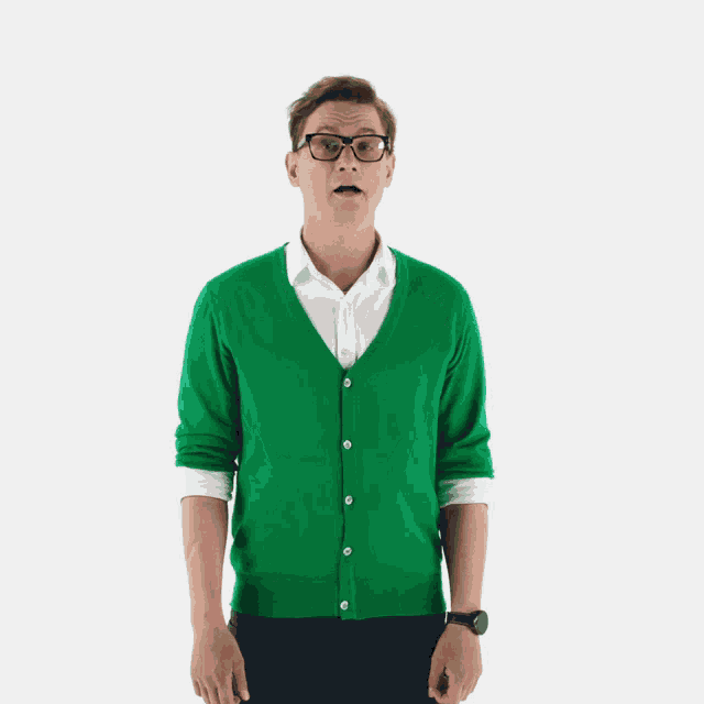 a man wearing glasses and a green sweater is making a funny face