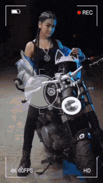 a video of a woman standing next to a motorcycle is being recorded