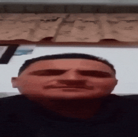 a man with a mustache is making a funny face while sitting in front of a keyboard .