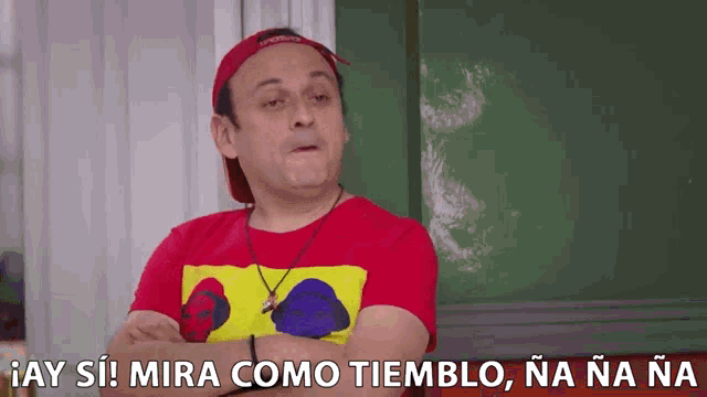 a man wearing a red shirt and a hat says mira como tiemblo na na na