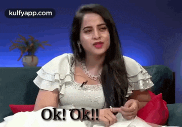 a woman in a white dress is sitting on a couch and says ok ! ok !