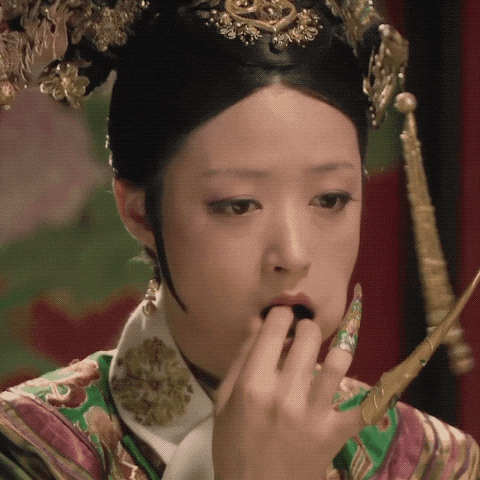 a woman with a crown on her head is licking her nails