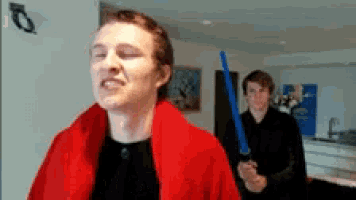a man wearing a red robe is holding a blue light saber