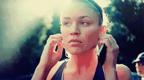 a woman is talking on a cell phone while putting on ear plugs .