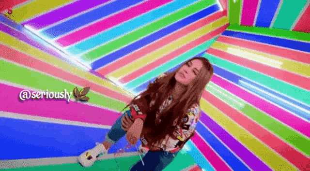 a girl is sitting in front of a rainbow colored wall with the words seriously written on the bottom