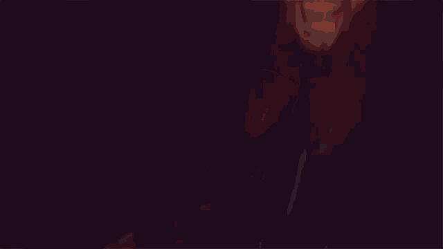 a man with a beard is laughing in the dark with his mouth open .