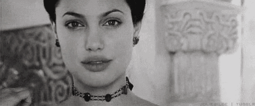 a black and white photo of a woman wearing a necklace and earrings .