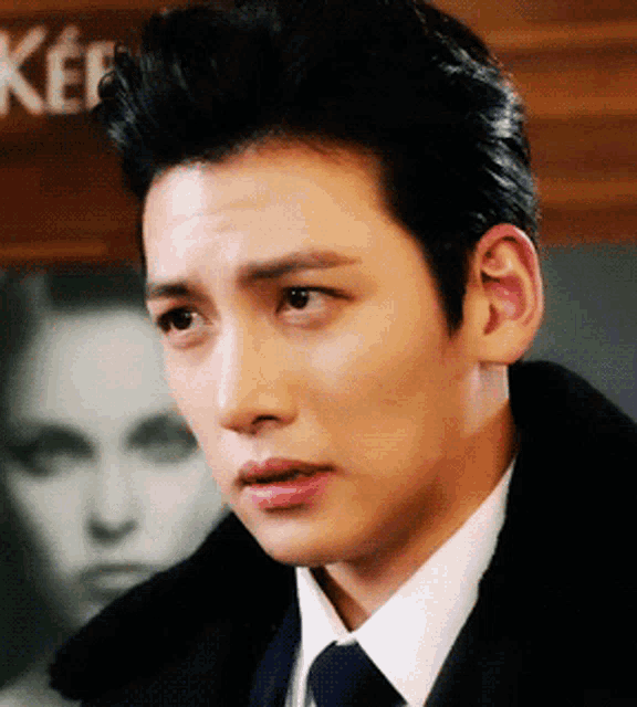 a man in a suit and tie stands in front of a sign that says keep