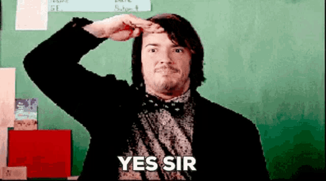 a man salutes in front of a green board with the words yes sir written on it
