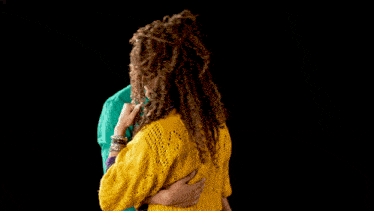 a man in a green shirt and a woman in a yellow sweater are standing next to each other
