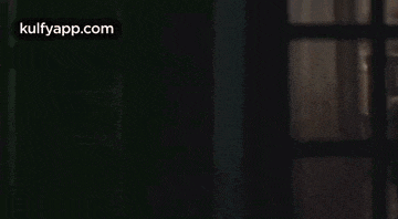 a man with a beard is sitting at a table in a dark room with candles .