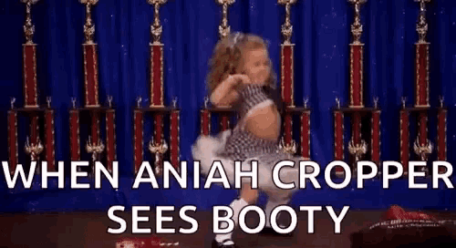 a little girl is dancing in front of trophies with the words `` when aniah cropper sees booty '' .
