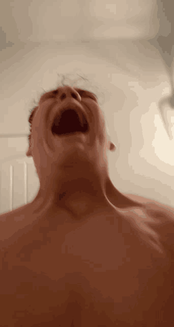 a man without a shirt is screaming with his mouth open