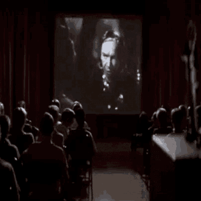 a group of people are watching a movie on a screen in a theater .
