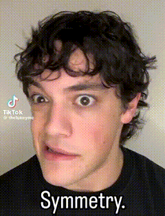 a man with curly hair is making a funny face with the words `` symmetry '' written on his face .