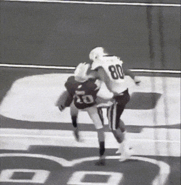 a football player with the number 80 on his jersey is tackled by another player