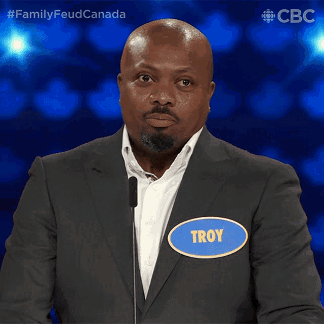 a man in a suit has a name tag that says troy on it
