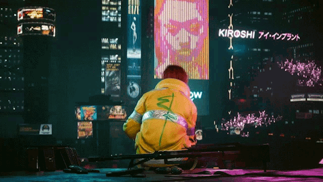 a man in a yellow jacket is kneeling in front of a large screen that says kirosh