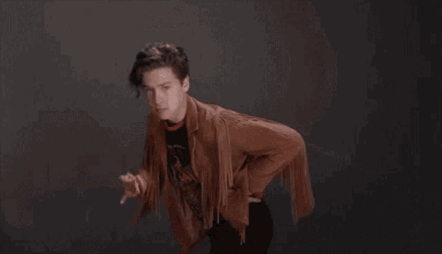 a young man in a leather jacket is eating a hamburger .