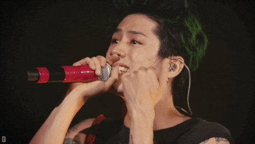 a person with green hair singing into a microphone