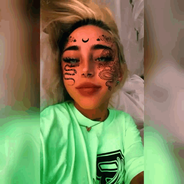 a woman in a green shirt has a tattoo on her face