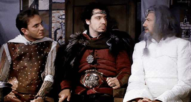 a man with a crown on his head is sitting between two other men