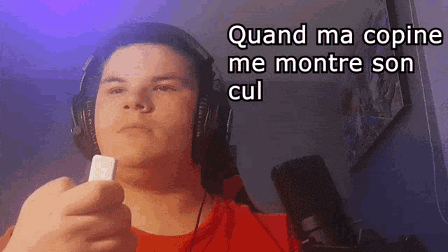a man wearing headphones and holding a cell phone with the words " quand ma copine me montre son cul " above him