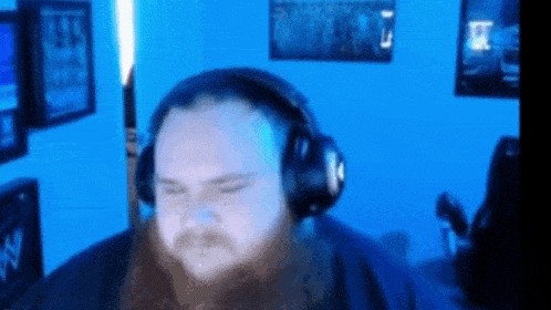 a man with a beard wearing headphones is sitting in a room .