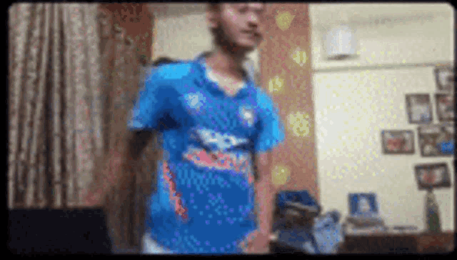a man in a blue shirt is standing in a room with a lot of pictures on the wall .