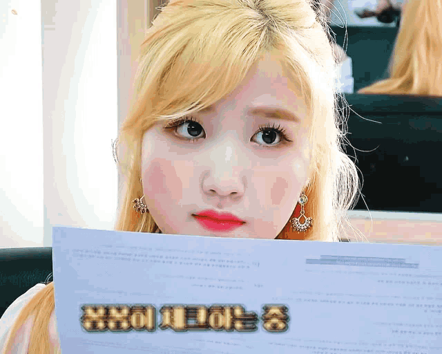a close up of a woman holding a piece of paper with a foreign language displayed on it