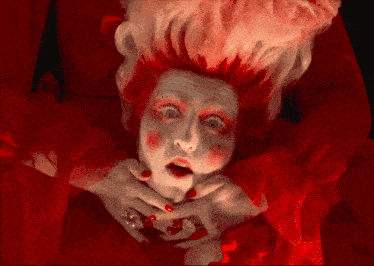 a woman in a red dress with white hair and red nails