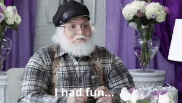 a man with a beard and mustache is sitting at a table with flowers in front of him .