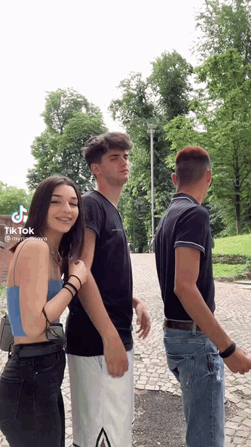 a girl in a blue tank top is standing next to two men .