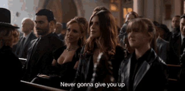 a group of people are sitting in a church and one of them says never gonna give you up .