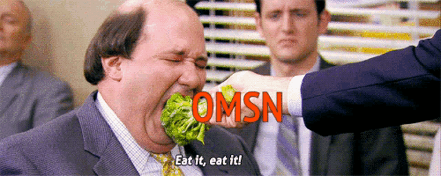 a man in a suit and tie is being told to eat the lettuce