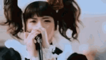 a young girl is singing into a microphone while wearing a maid outfit .