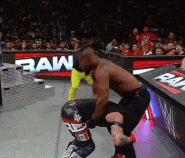 a wrestling match takes place in front of a raw sign
