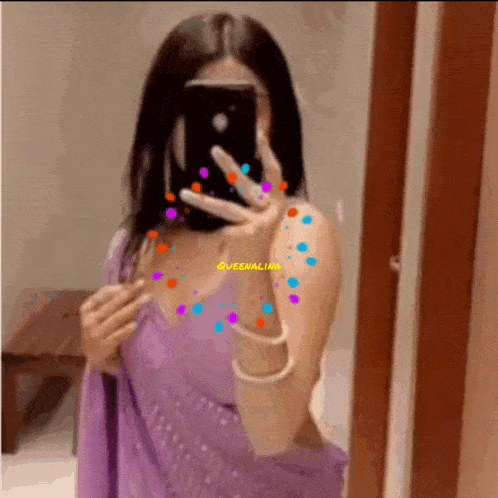 a woman in a purple dress is taking a picture of herself in a mirror .