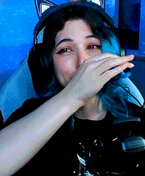 a woman with blue hair is wearing headphones and covering her mouth .
