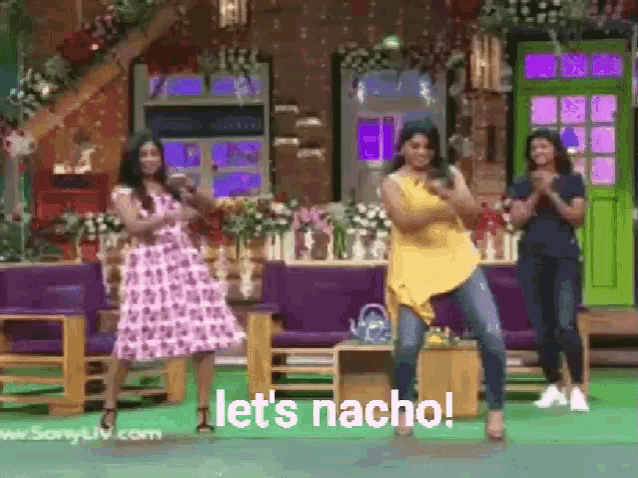 a group of women are dancing in front of a couch and a green door .
