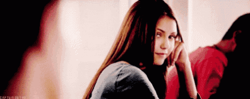 a woman is sitting in front of a mirror looking at herself in the mirror .