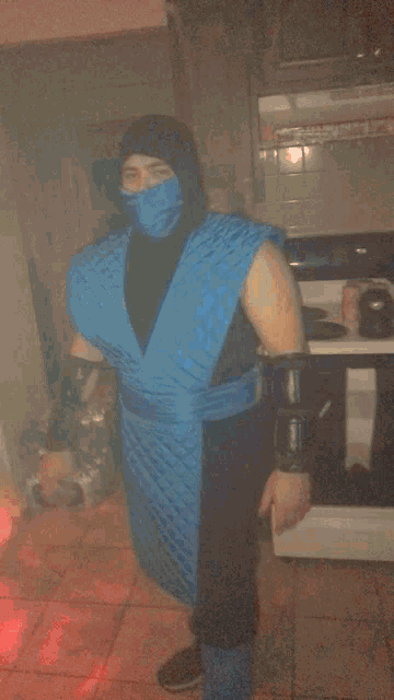a man in a blue ninja costume is standing in a dark room