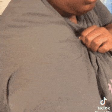 a man wearing a grey shirt with the word tiktok written on the bottom